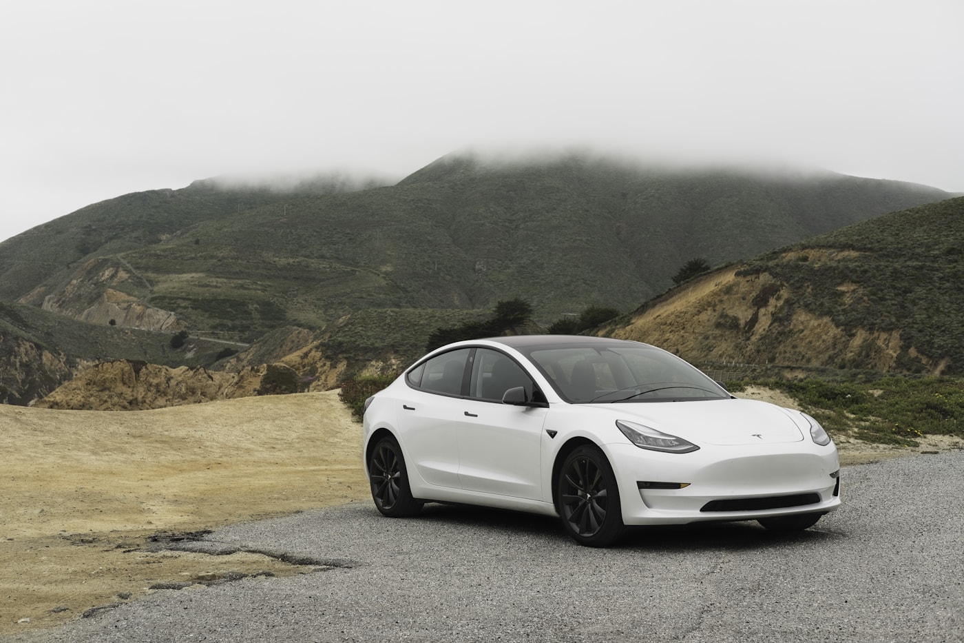 A white electric car travelling on an open road